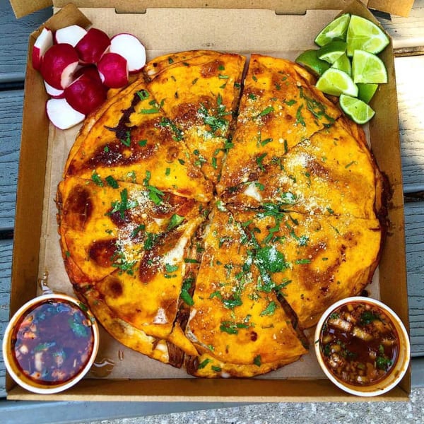 El Agave Azul's large birria quesadilla, cut into slices, with radishes, limes, and two dipping sauces.